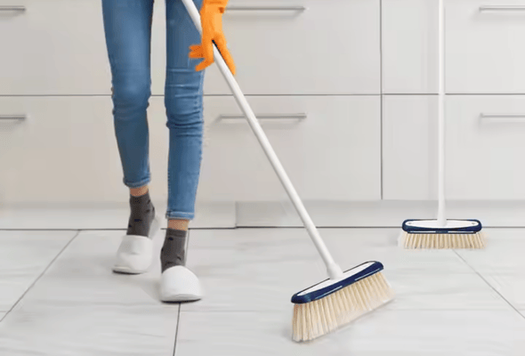 Person sweeping the floor with a broom