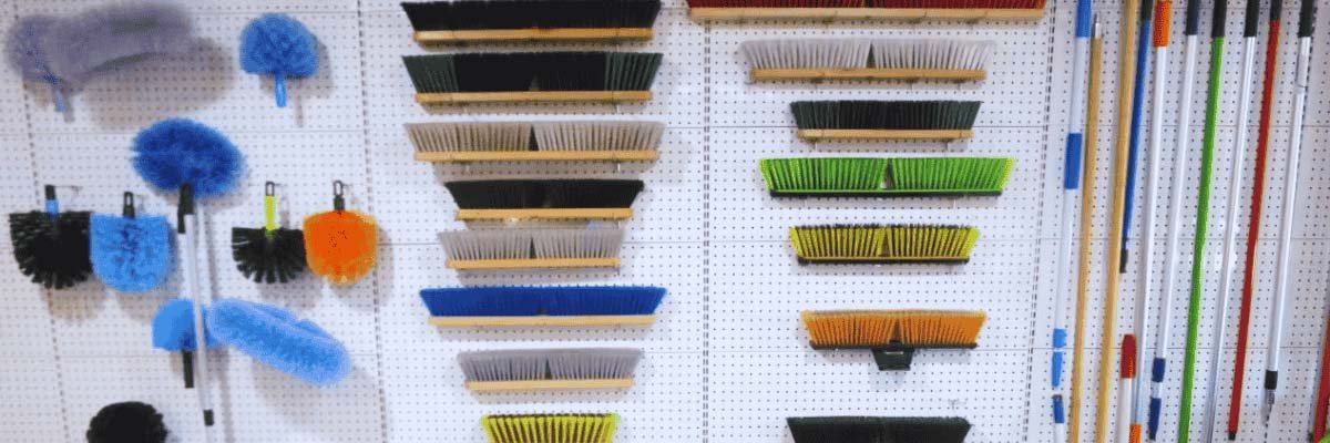 Various cleaning tools and mop heads displayed on a wall, arranged neatly in rows